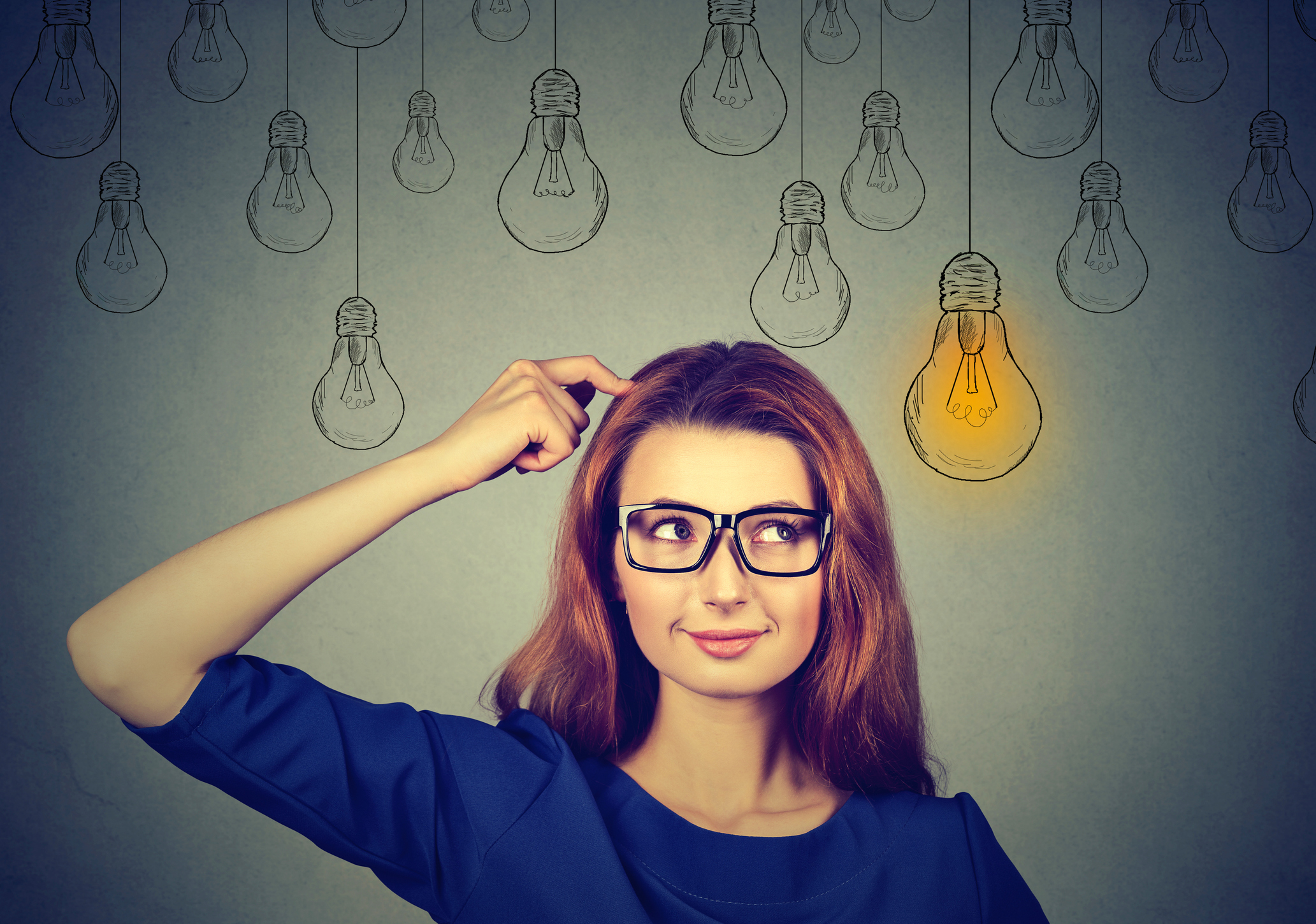 woman in glasses looking up at light idea bulb